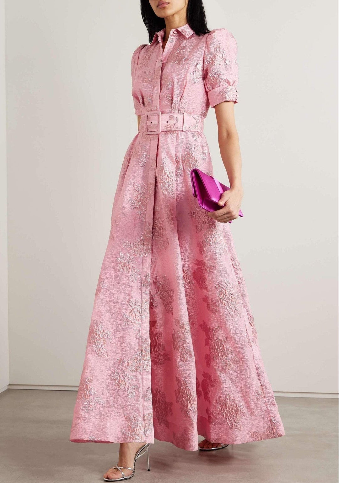 Woman wearing a pink dress with floral patterns against a plain background